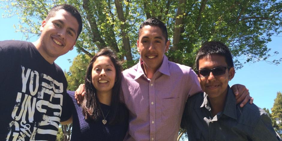 3 young men, 1 young woman smiling outside under a tree in Gonzales