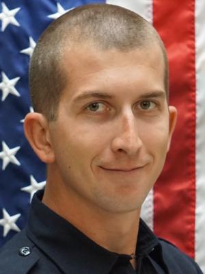 Photo of David Achen in front of a flag