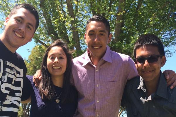 3 young men, 1 young woman smiling outside under a tree in Gonzales